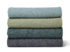 A collection of green and blue honeycomb patterned blankets stacked