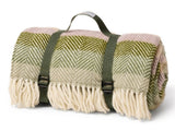 Woven blanket with green and pink pattern and carrying straps on a white background
