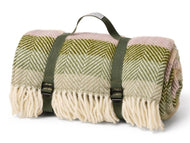 Woven blanket with green and pink pattern and carrying straps on a white background